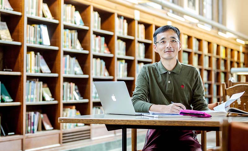 Student Kang Wu studying in the library stacks