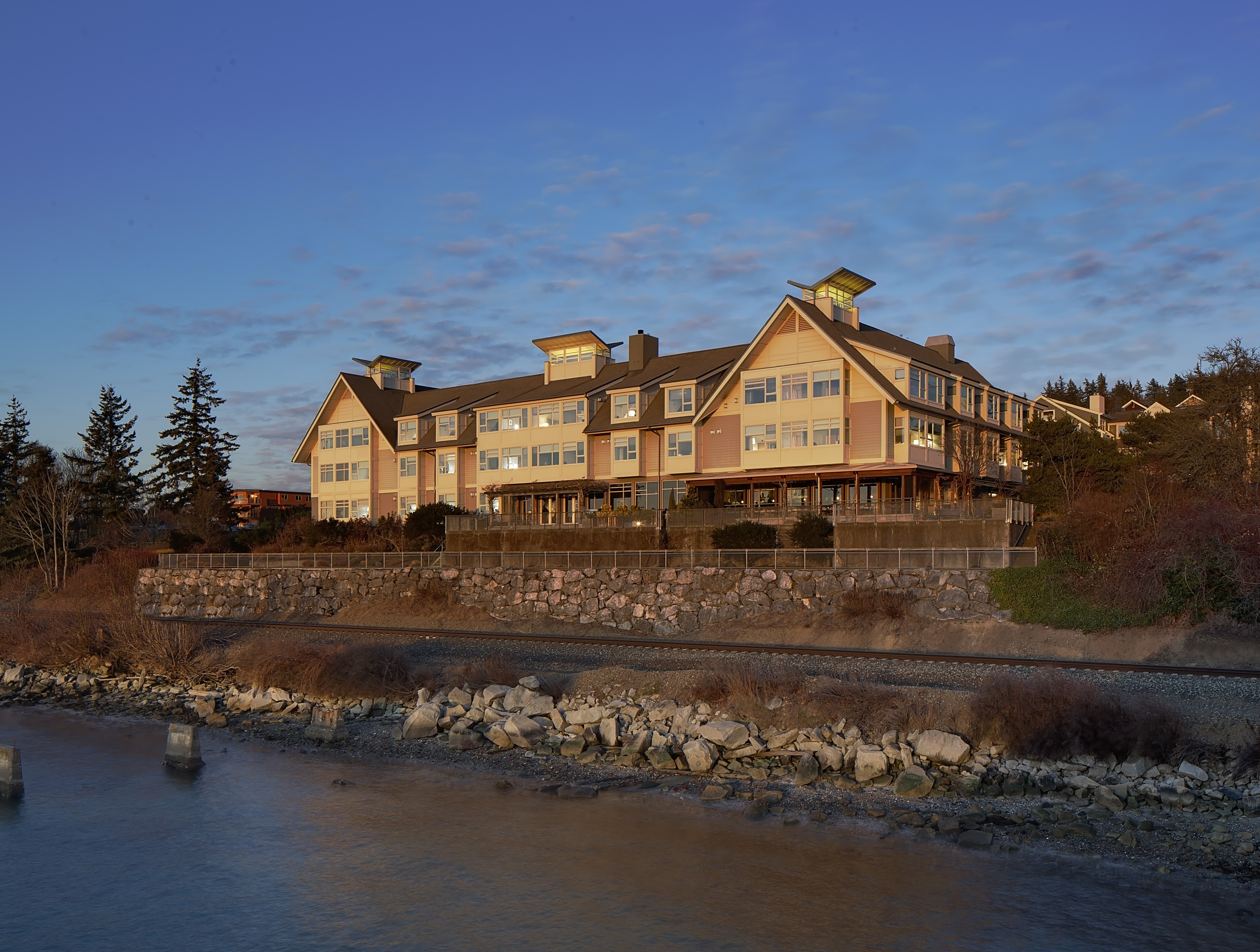 Rustic Hotel Chrysalis on the shore of Bellingham Bay with railroad tracks running below.