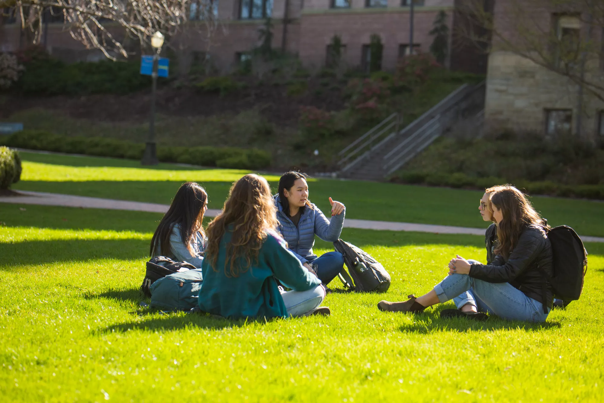 A group of students sitting on green grass outside Old Main having a discussion.