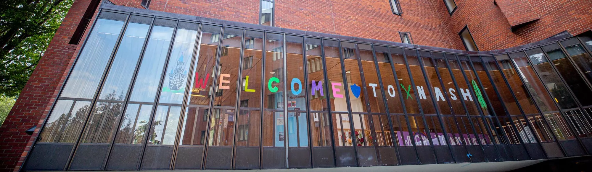 Hand lettered "Welcome to Nash" sign inside the windows of Nash Hall