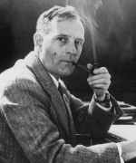 Edwin Hubble wears a suit jacket and smokes a cigar while giving a sideways glance