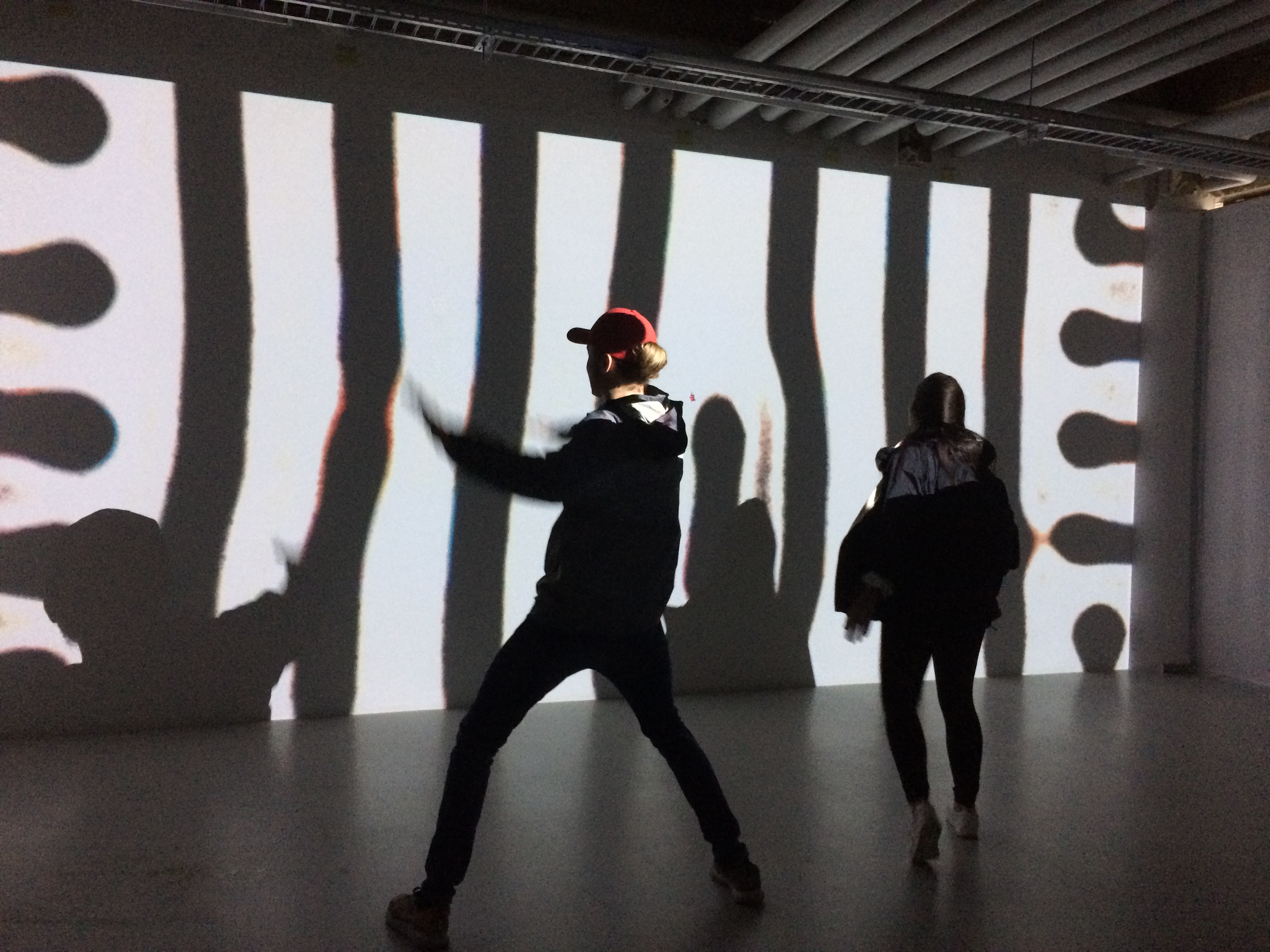 Two students pose in front of a shadow projection of graphic lines