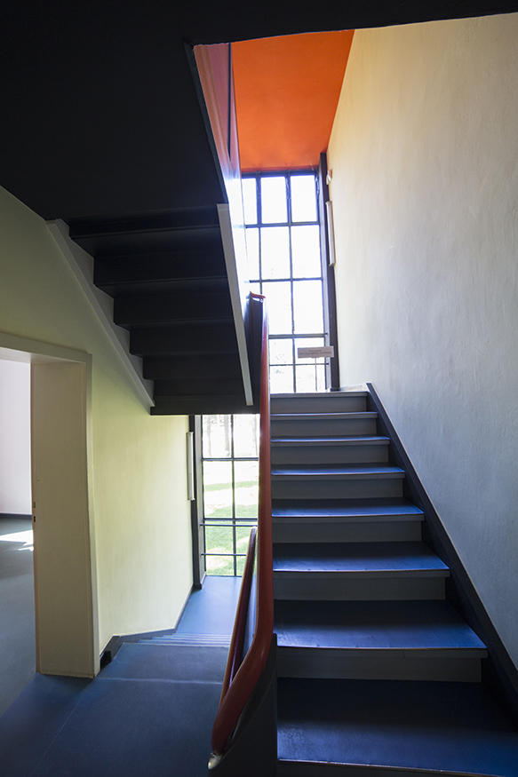 a black interior staircase with a red railing and red ceiling overhead