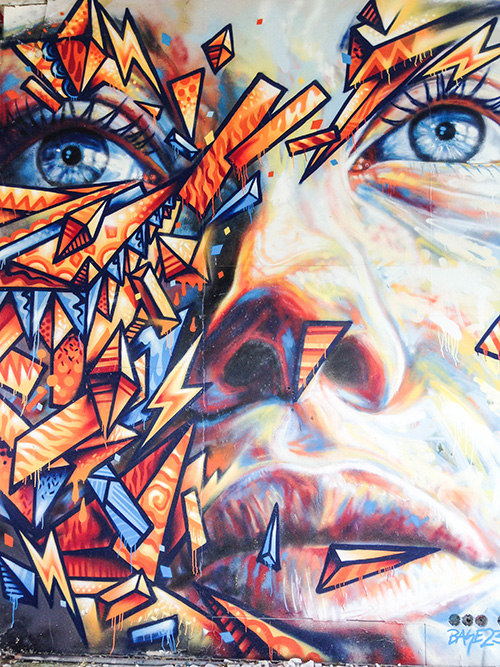 A mural containing bold gaphic geometric shapes overlayed on a painterly close up of a woman's face