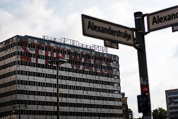 A building with the words 'stop wars' painted on its side. Street signs say 'Alexanderstrasse' and 'Alexan...' in the foreground