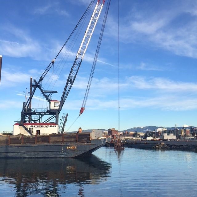 An American Construction boat floating along the Bellingham waterfront on a sunny day.