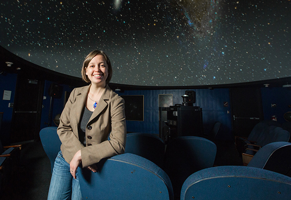 Melissa leans againts a seat in the Planetarium