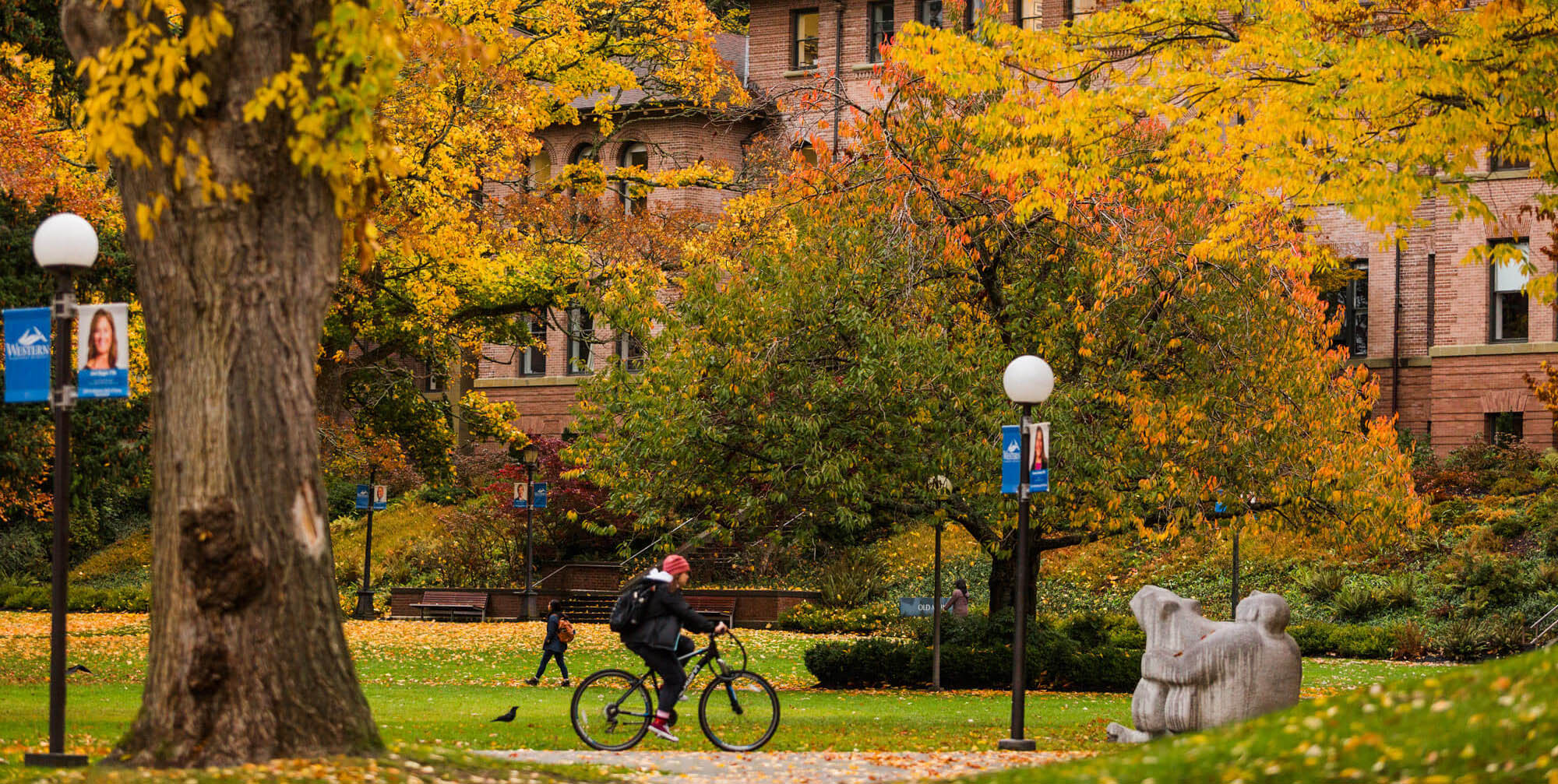 Fall foliage on WWU's campus with students walking their bikes.