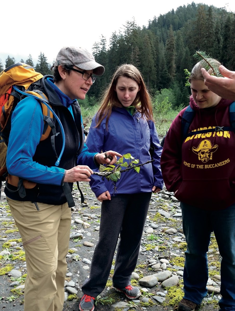 Dr. Jenise Bauman examining a branch with two students.