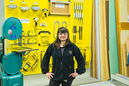 A Western student in front of a yellow wall of tools