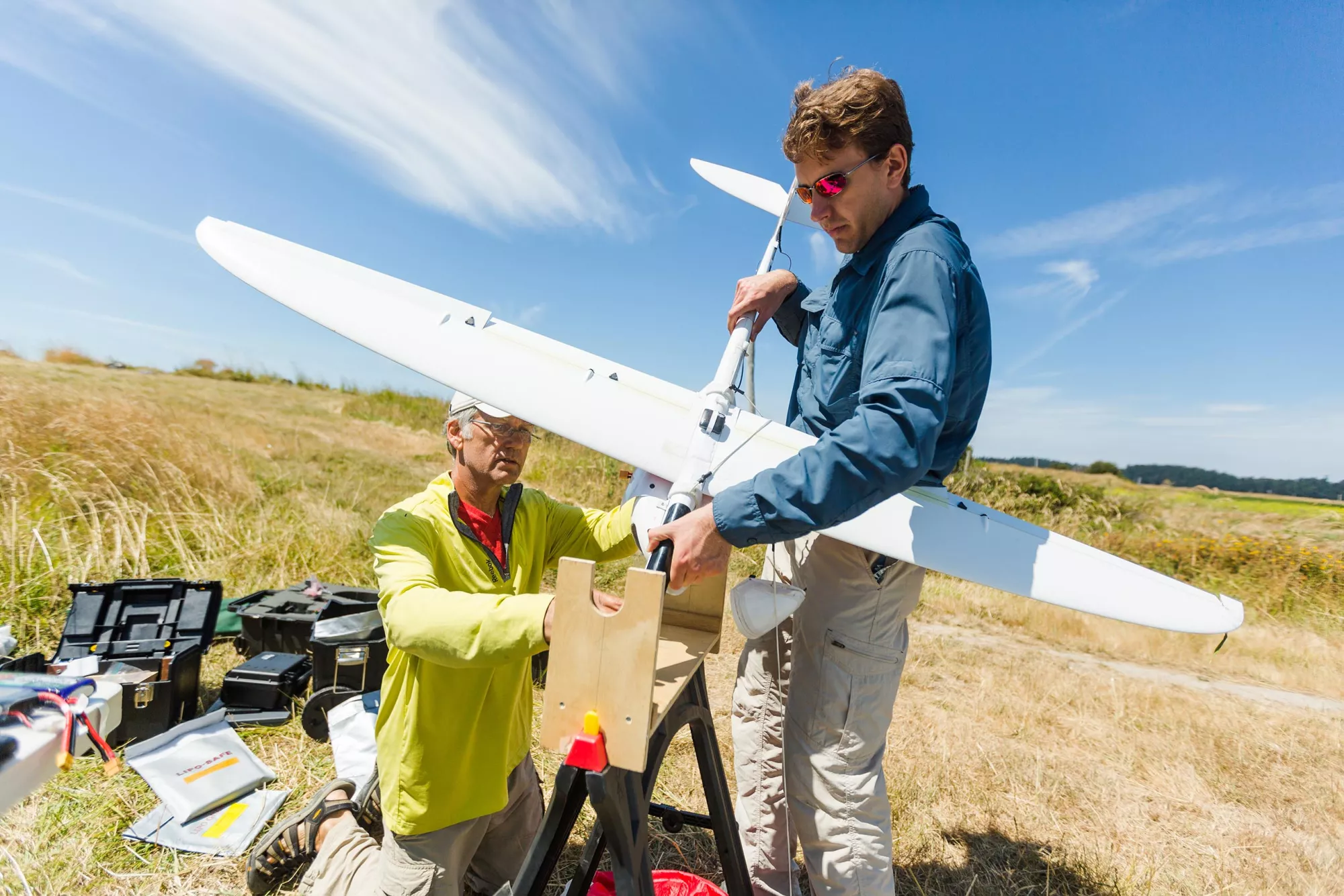 Two men wrangling a model airplane