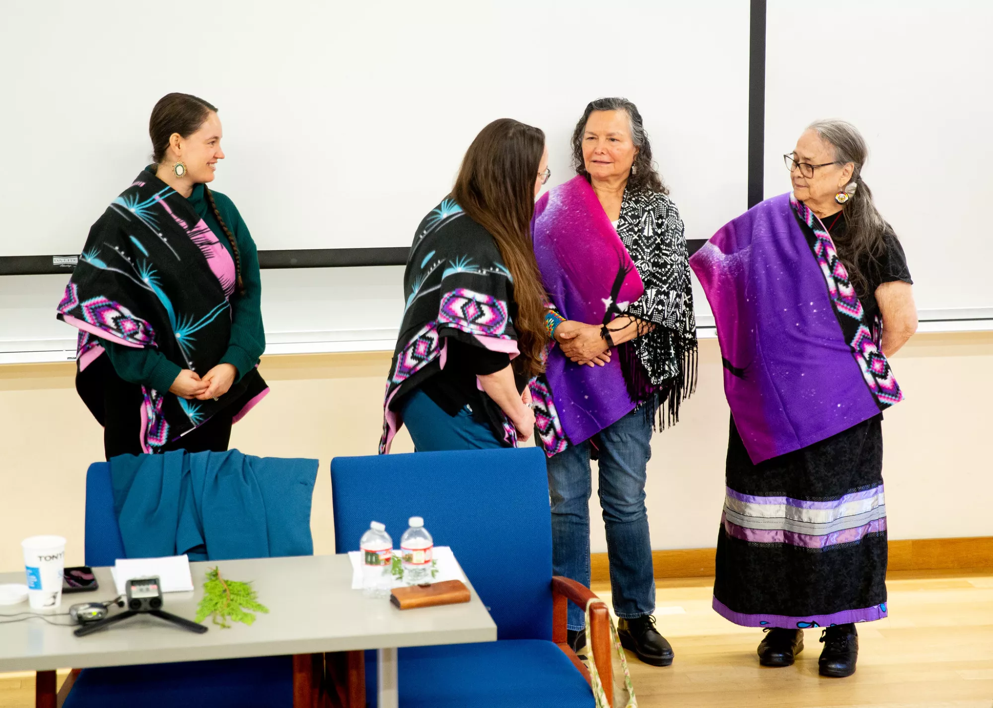 Four Native women at the Hidden Figures events wearing colorful shawls