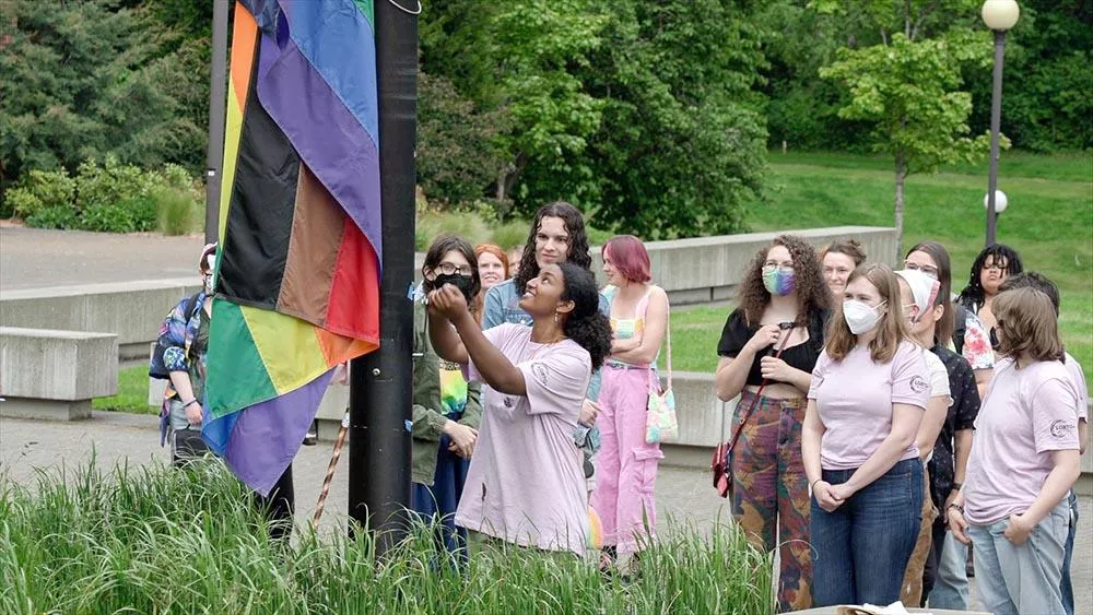A diverse group of students raising a flag at a pride celebration