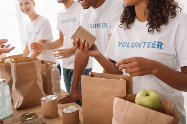 A row of volunteers fill sack lunches