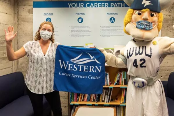 A Western employee stands with Victor the Viking holding up a Career Services Center blue tshirt.