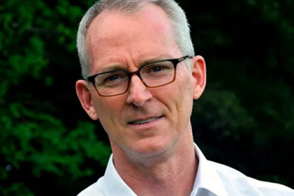 Bob Inglis is a light-skinned male with short grey hair. He smiles and wears brown-rimmed glasses and a white shirt.