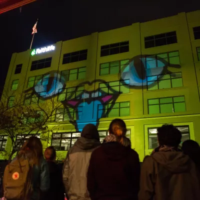 Motion design student work projected onto the side of a large building.