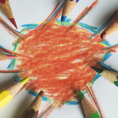 Colored pencils surrounding a drawing of an orange circle with a blue outline.