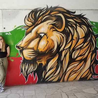 Student standing next to a painted mural of a lion's head in Plodiv, Bulgaria.