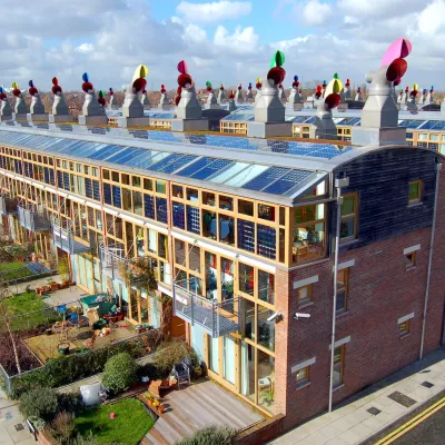 Large sustainable buildings with many windows, brick walls, and colorful wind cowls that circulate air. There is plenty of green space and sidewalks.