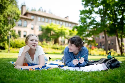 Two students relax on the lawn in front of Old Main.