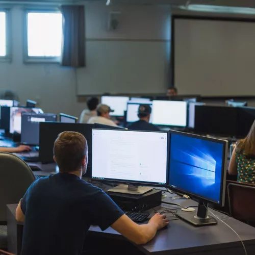 Students sit at computers in a lab.