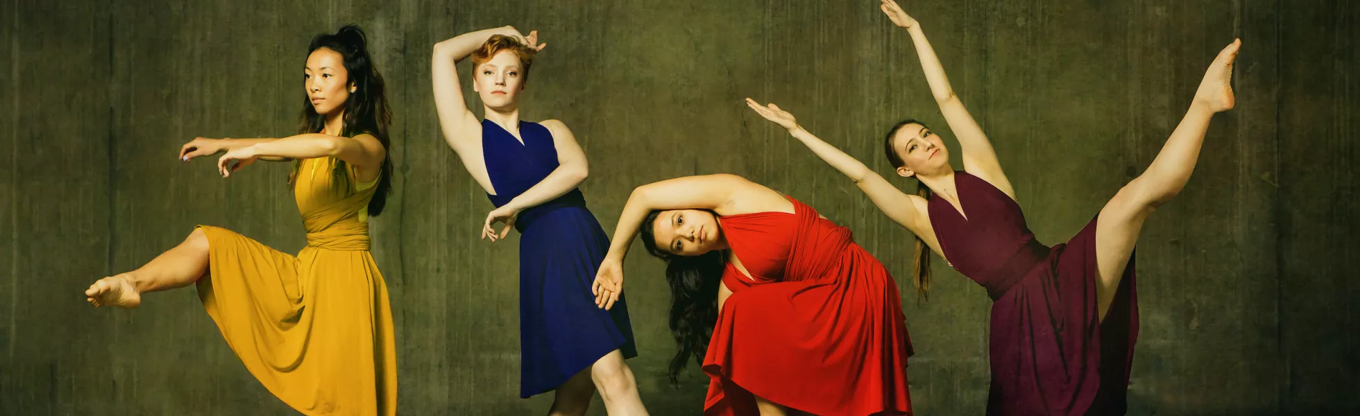 4 dancers in various poses wearing yellow, navy, red, and plum dresses.