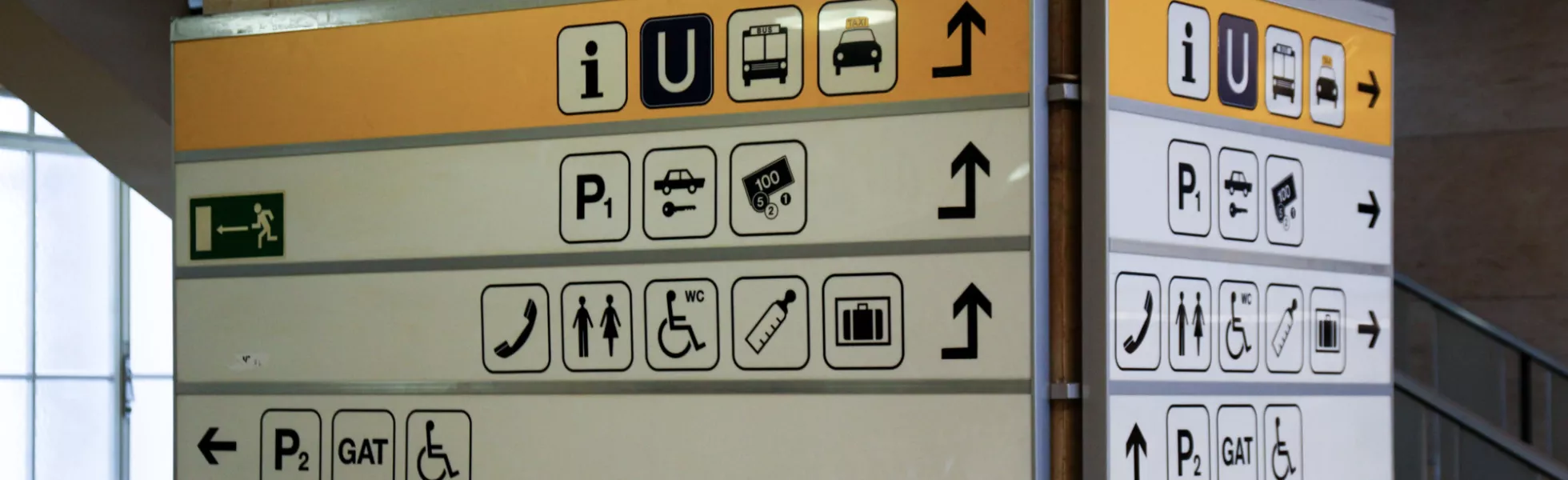 Multiple symbols on a sign on a pillar in a German airport.