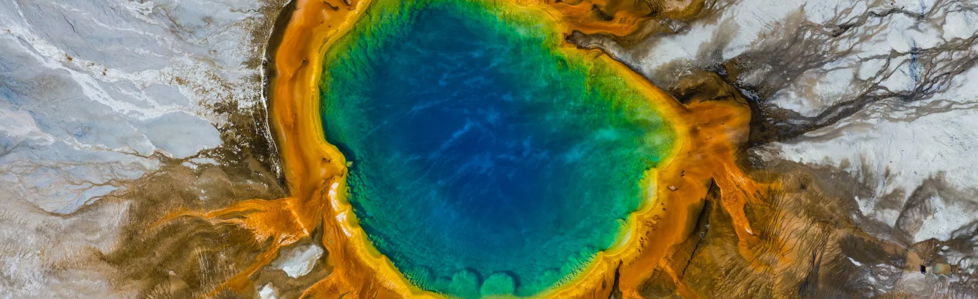 Aerial view of Grand Prismatic Spring in Yellowstone National Park. Huge rainbow colored hot spring in a field of salty white.