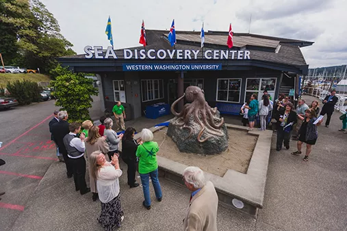 photo of outside of sea discovery center in Poulsbo with a group of people surrounding a statue of an octopus.
