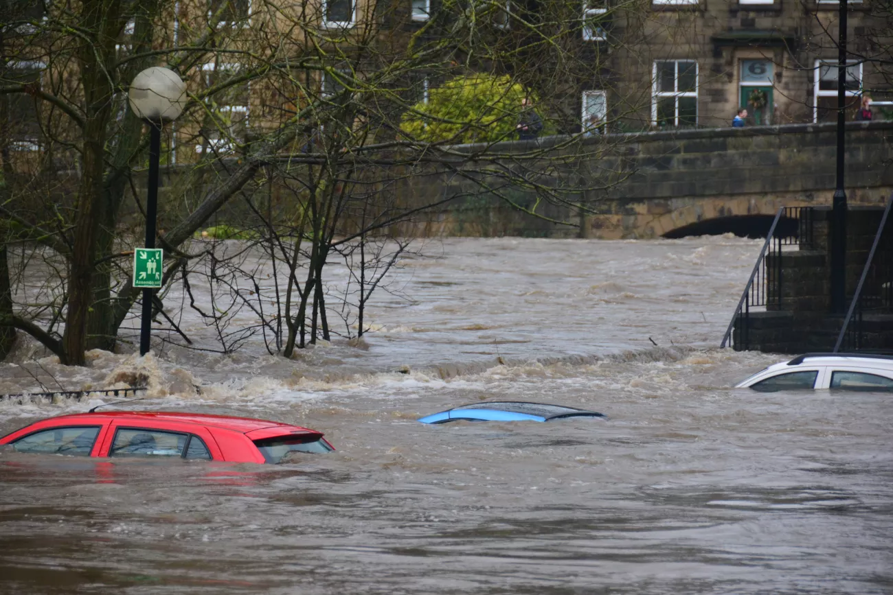 3 cars on the street submerged under water in a flood.