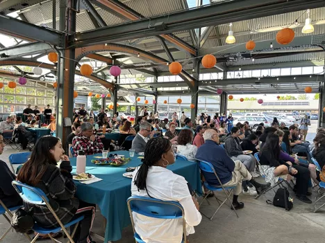 People from 2023's festival sitting at tables, looking towards the stage