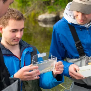 Students holding small plastic containers containing fish