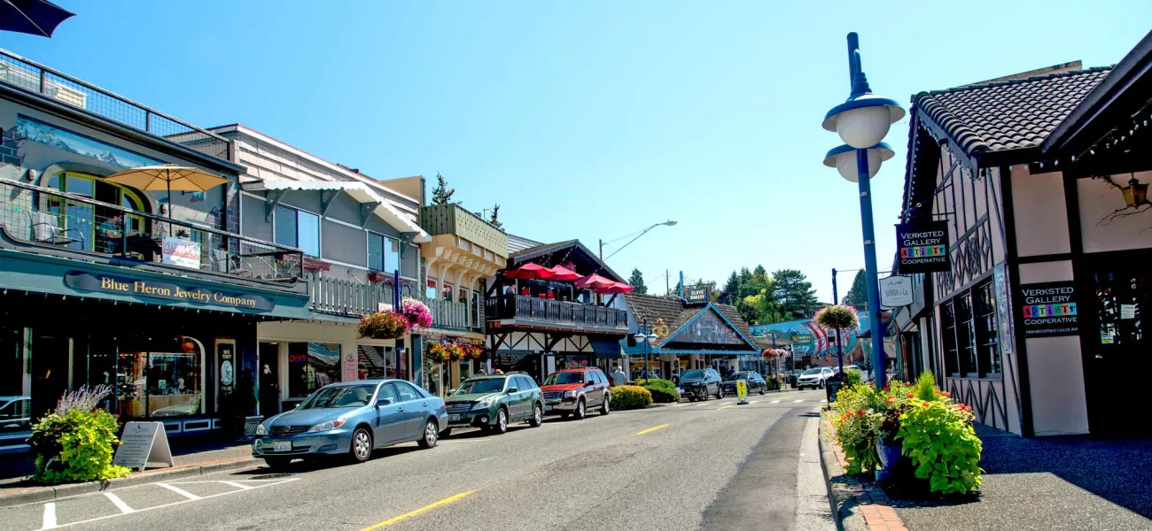 A shot of the quaint small shops of downtown Poulsbo. The streets are lined with with cars on this sunny, blue sky day.