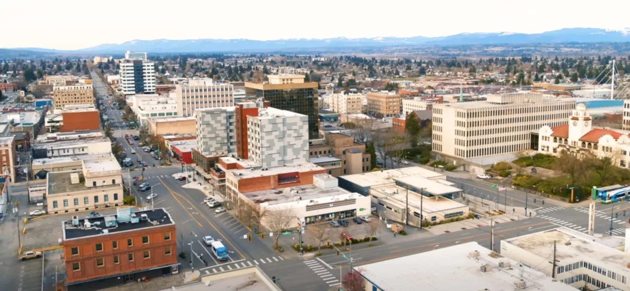 A panorama image of the Everett city skyline. Buildings stretch as far as you can see. Mountains line the background in the distance.
